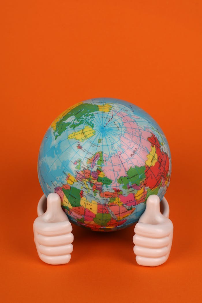 Vibrant photo of hands holding a globe against an orange backdrop.